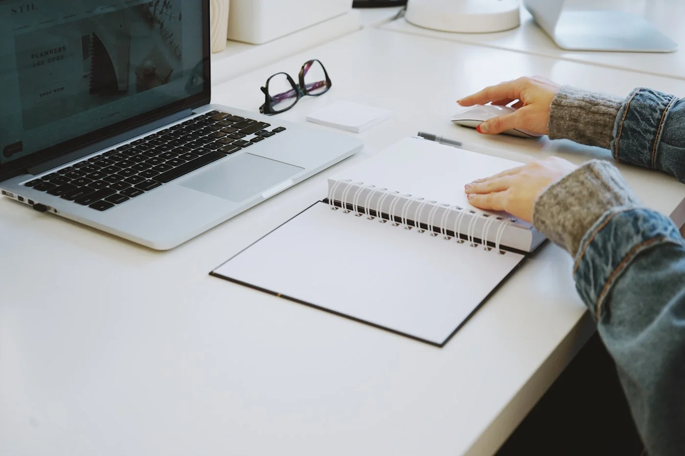 A calm desk with a laptop, reading glasses and an open notebook